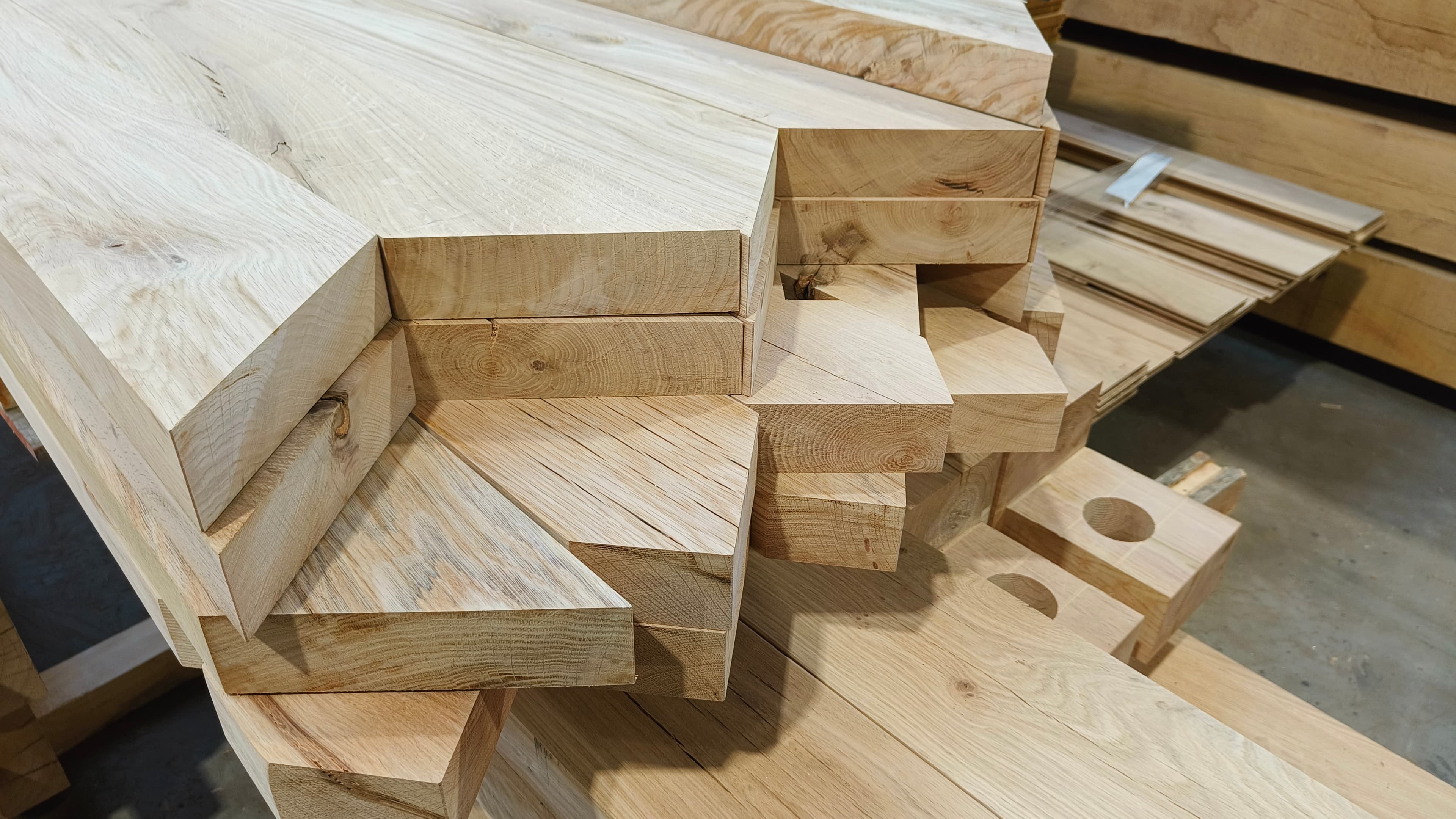 Stapel lichte houten planken en balken in een houtbewerkingsruimte.